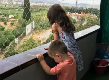 Dos niños asomados a un balcón protegido por red de seguridad